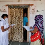 FILE PHOTO: Health workers collect personal data from a man as they prepare a list during a door-to-door survey on the outskirts of Ahmedabad