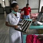 A paramedic distributes free medicine provided by the government to patients inside a ward at RGGGH in Chennai