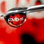 FILE PHOTO: The word "COVID-19" is reflected in a drop on a syringe needle in this illustration