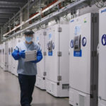 Image: FILE PHOTO: A worker passes a line of freezers holding coronavirus disease (COVID-19) vaccine candidate BNT162b2 at a Pfizer facility in Puurs