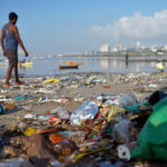 FILE PHOTO: A man walks on a garbage-strewn beach in Mumbai