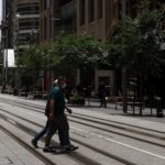 A person in a protective face mask crosses a street in Sydney