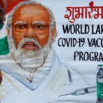 FILE PHOTO: A woman walks past a painting of Indian Prime Minister Narendra Modi a day before the inauguration of the COVID-19 vaccination drive on a street in Mumbai
