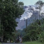 Locals walk on a road as Mount Merapi volcano spews hot ash in Kaliurang, Sleman, Yogyakarta