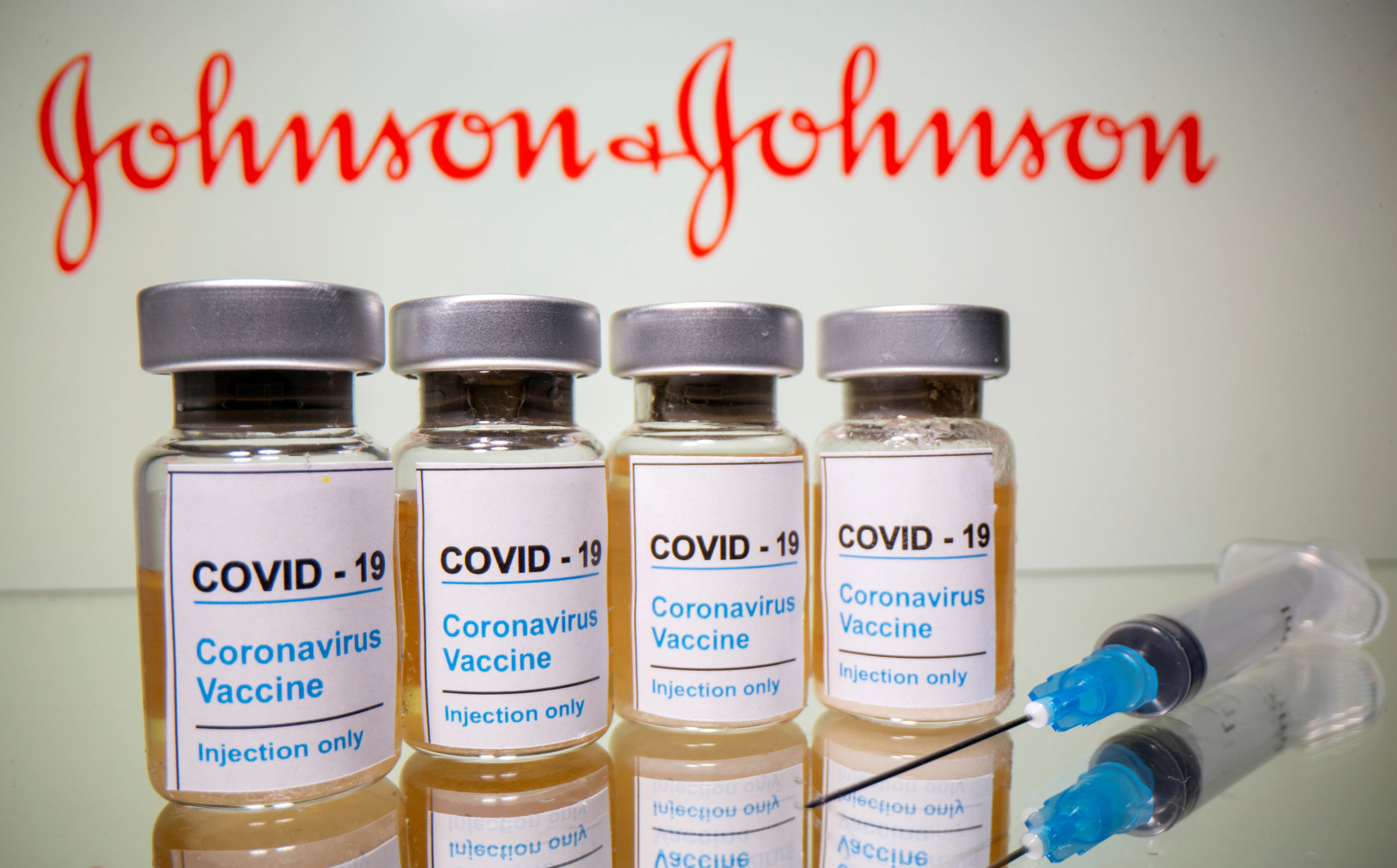 Vials and medical syringe are seen in front of J&J logo in this illustration. Illustration: Reuters/Dado Ruvic/Illustration