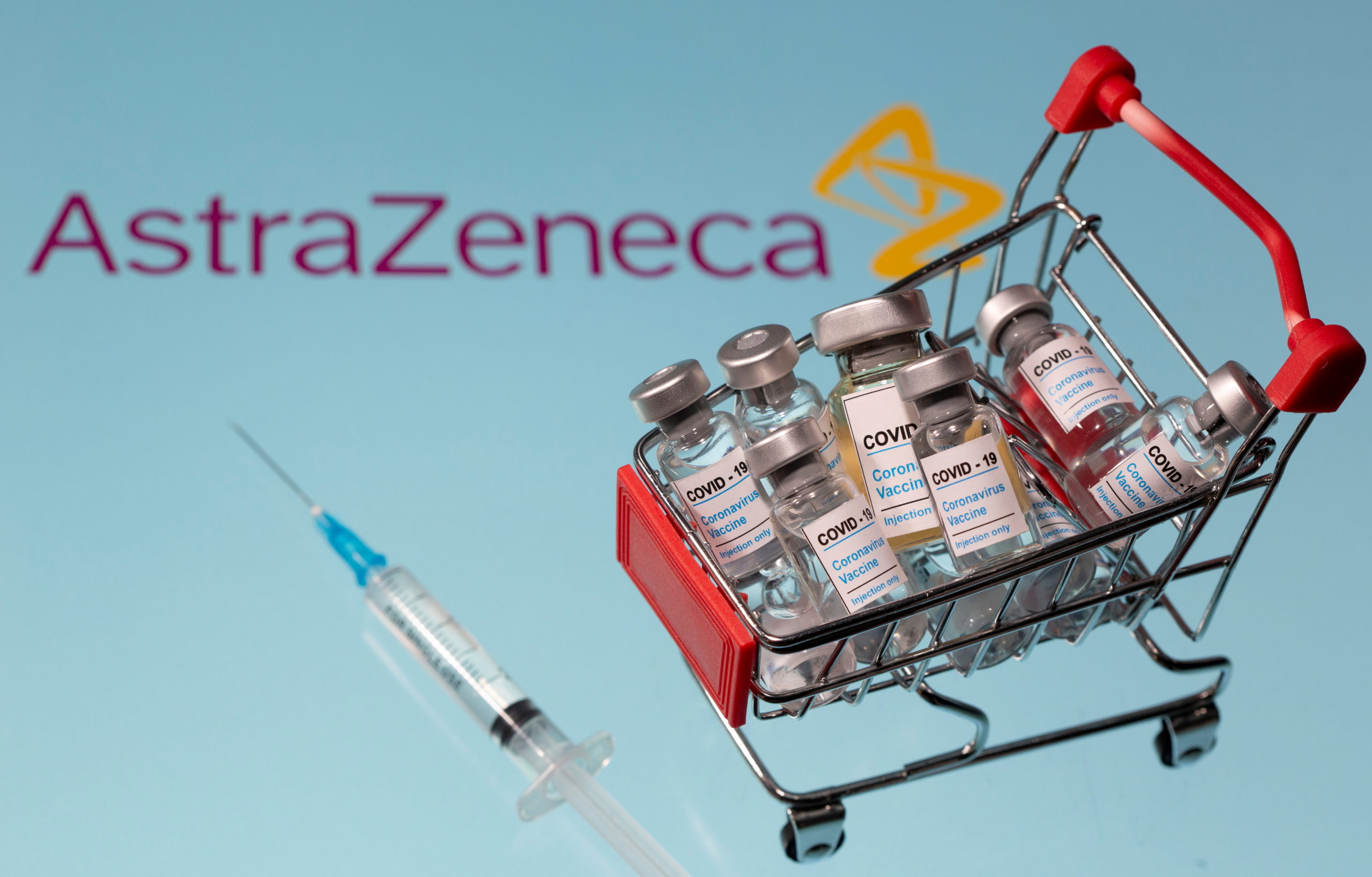 A small shopping basket filled with vials labeled "COVID-19 - Coronavirus Vaccine" and a medical sryinge are placed on an AstraZeneca logo. Photo: Reuters/Dado Ruvic/Ilustration/File Photo