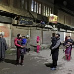 Residents carrying their children stand on a road after vacating their houses following an earthquake in Srinagar