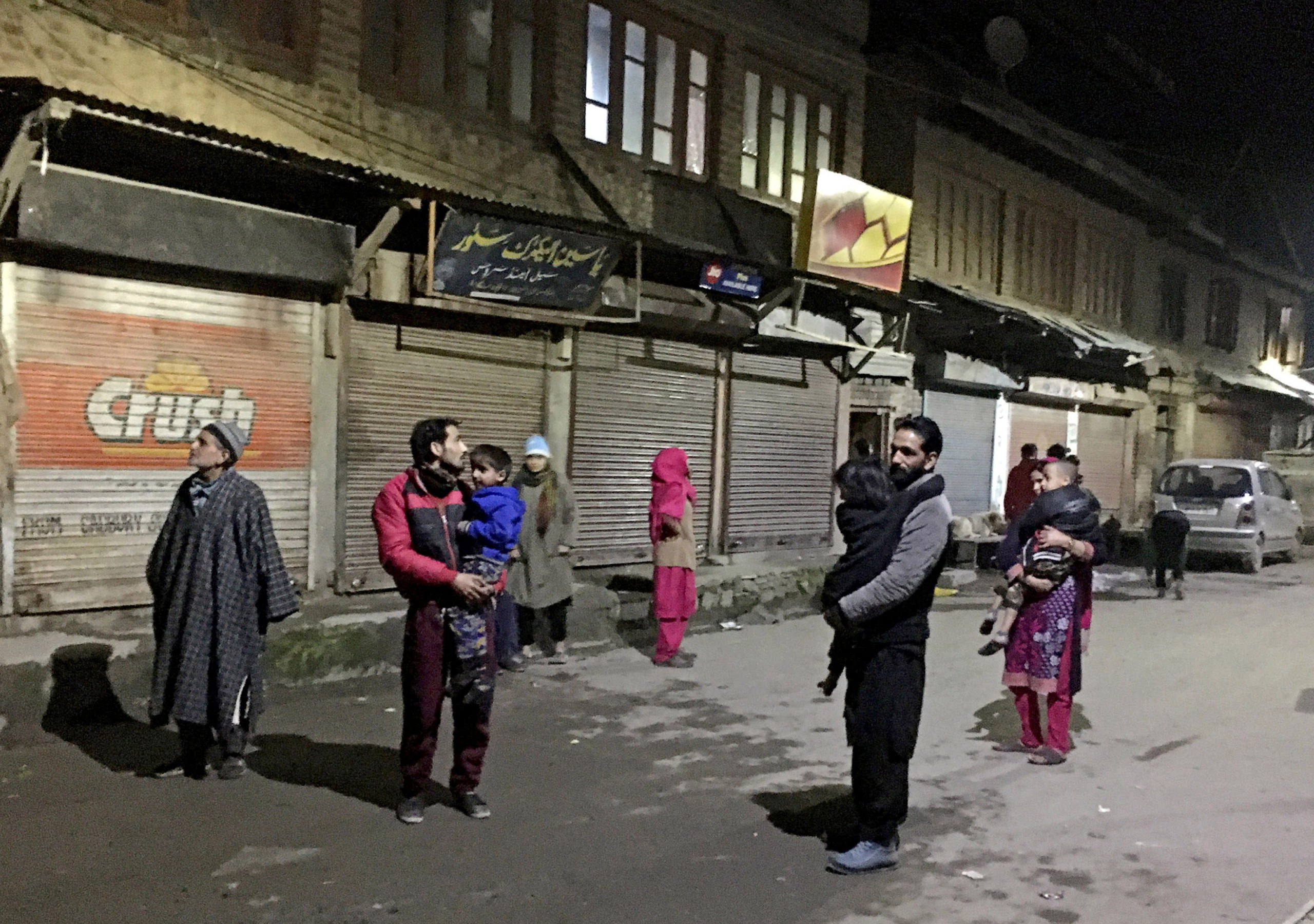 Residents carrying their children stand on a road after vacating their houses following an earthquake in Srinagar