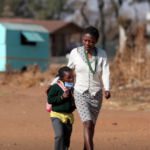 A woman walks with her daughter as schools reopen amid a nationwide coronavirus disease (COVID-19) lockdown in Eikenhof, south of Johannesburg, South Africa August 24, 2020.
