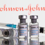 Vials labelled "COVID-19 Coronavirus Vaccine" and sryinge are seen in front of displayed J&J logo in this illustration