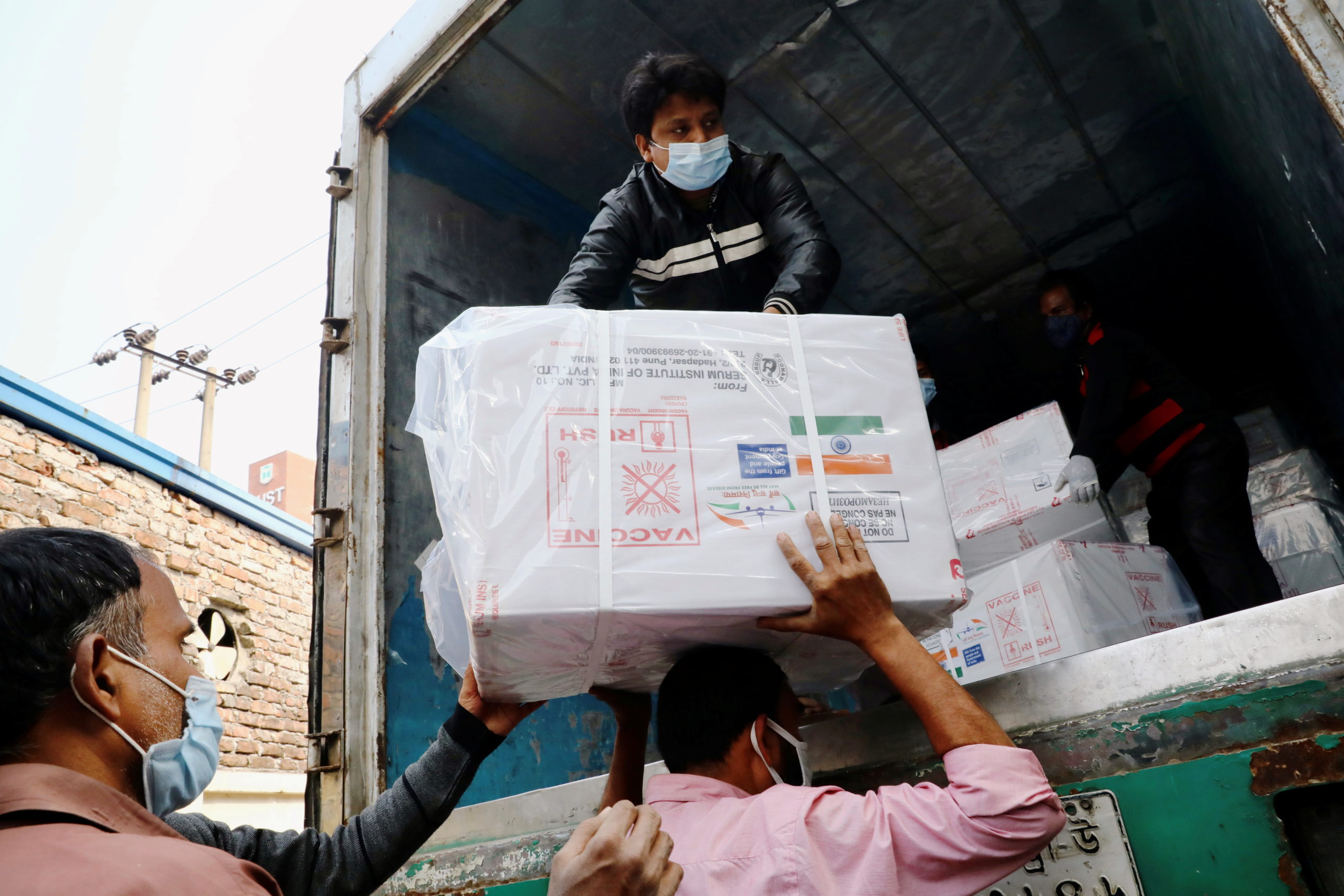 Workers unload a pickup van that carries Oxford-Astrazeneca COVID-19 vaccines which arrived from India as a gift to Bangladesh, in Dhaka