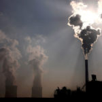 FILE PHOTO: A coal-burning power plant can be seen behind a factory in the city of Baotou, in China's Inner Mongolia Autonomous Region