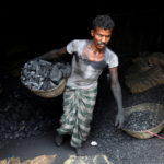FILE PHOTO: A worker carries coal in a basket in a industrial area in Mumbai
