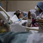 A medical worker tends to a patient suffering from COVID-19, inside the ICU ward at Holy Family Hospital in New Delhi