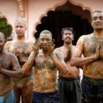 People pray after applying cow dung on their bodies during "cow dung therapy" on outskirts of Ahmedabad