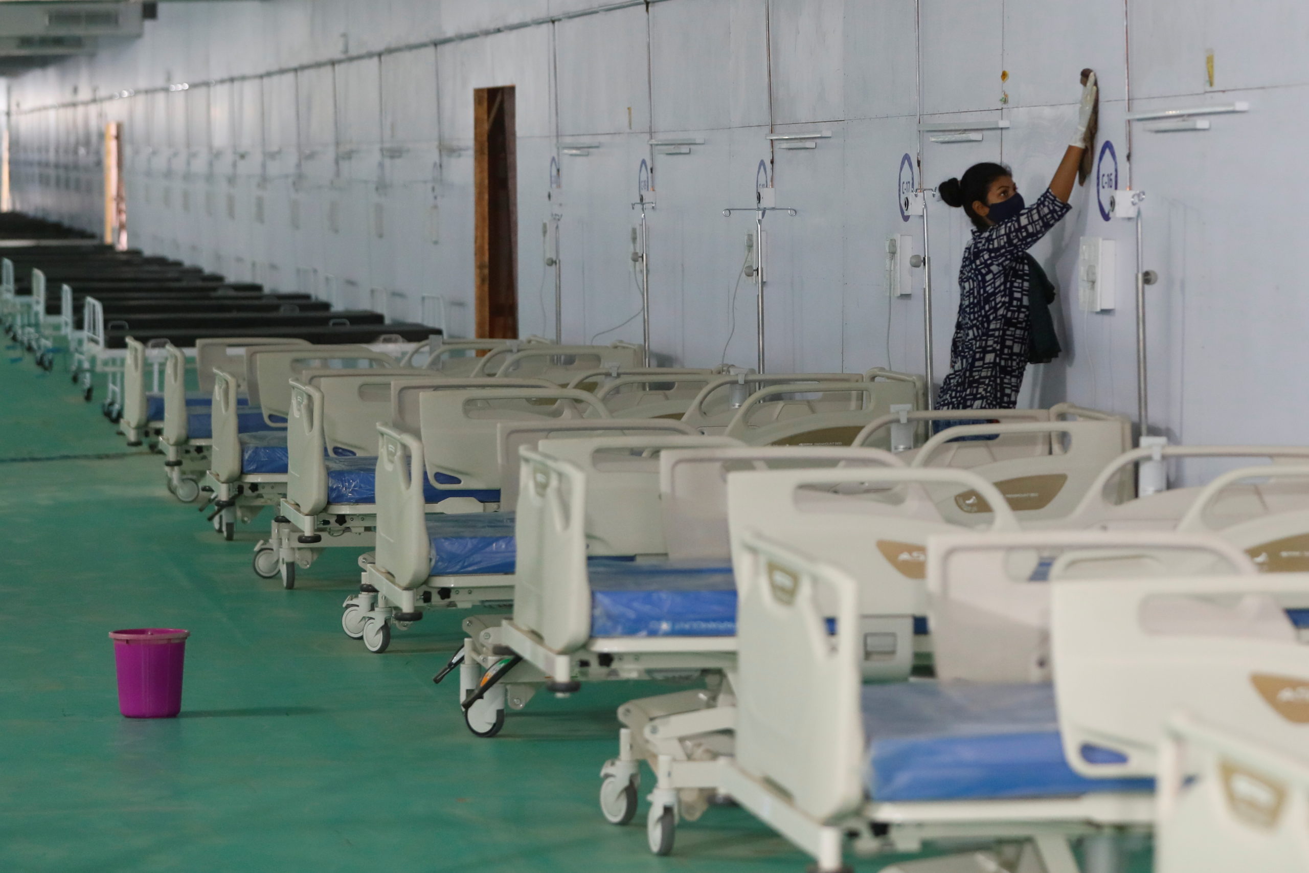 Worker cleans wall at temporary COVID-19 care facility in New Delhi