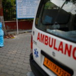A health worker rests as he sits next to his ambulance carrying a dead body of a victim who died due to the coronavirus disease (COVID-19), at a crematorium