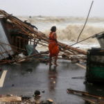 A woman stands next to her stall damaged by heavy winds at a shore ahead of Cyclone Yaas in Bichitrapur