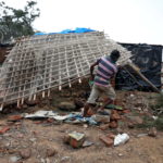 A man removes bamboo rooftop of a damaged hut following Cyclone Yaas in Digha