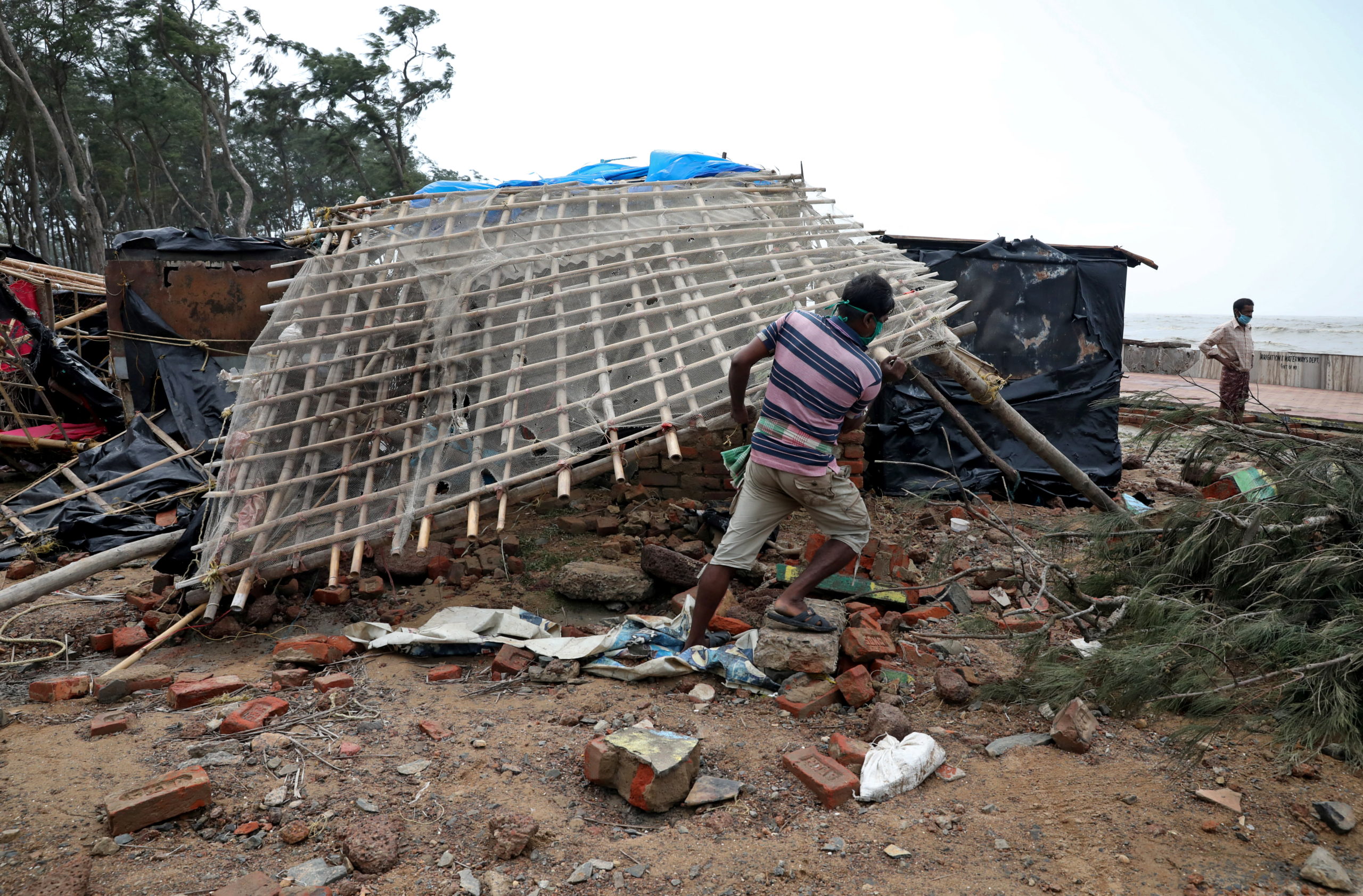A man removes bamboo rooftop of a damaged hut following Cyclone Yaas in Digha
