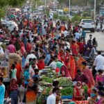 People shop at a crowded roadside vegetable market in Ahmedabad