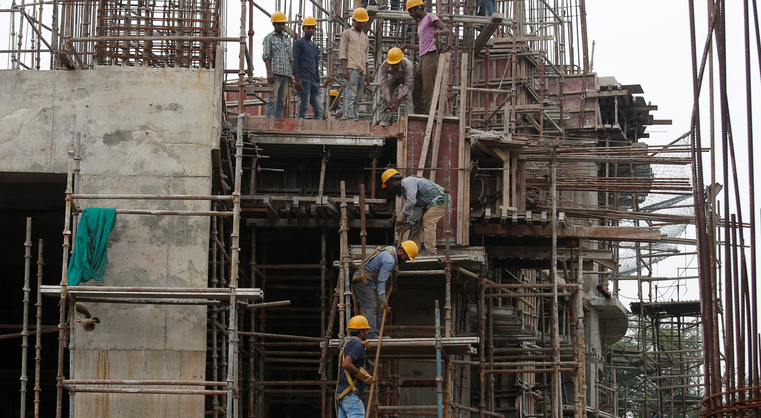 Workers erect scaffolding at a construction site of a metro rail station in Kolkata