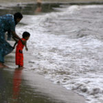 A child plays with his mother at a beach in Port Blair