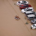 People on a makeshift raft make their way through a flooded road following heavy rainfall in Zhengzhou