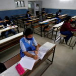 FILE PHOTO: Students wearing protective face masks attend their class as they maintain social distancing after authorities reopened schools for classes for 10 and 12, in Ahmedabad