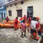 Members of National Disaster Response Force evacuate people to safer places from a flooded area in Udham Singh Nagar