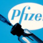 FILE PHOTO: Vial and sryinge are seen in front of displayed Pfizer logo