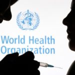 FILE PHOTO: People pose with syringe with needle in front of displayed WHO logo