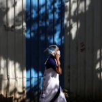 A woman wearing a protective face mask walks on a street, amidst the spread of COVID-19, in Mumbai