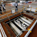 TEPCO employees are seen next to the part of an underground ice wall unit at tsunami-crippled Fukushima Daiichi nuclear power plant in Okuma town, Fukushima prefecture