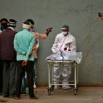 Men take photographs of the body of their relative after he died from the coronavirus disease (COVID-19) at a hospital in Ahmedabad