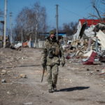 Ukrainian service member walks in a destroyed village on the front line in the east Kyiv region