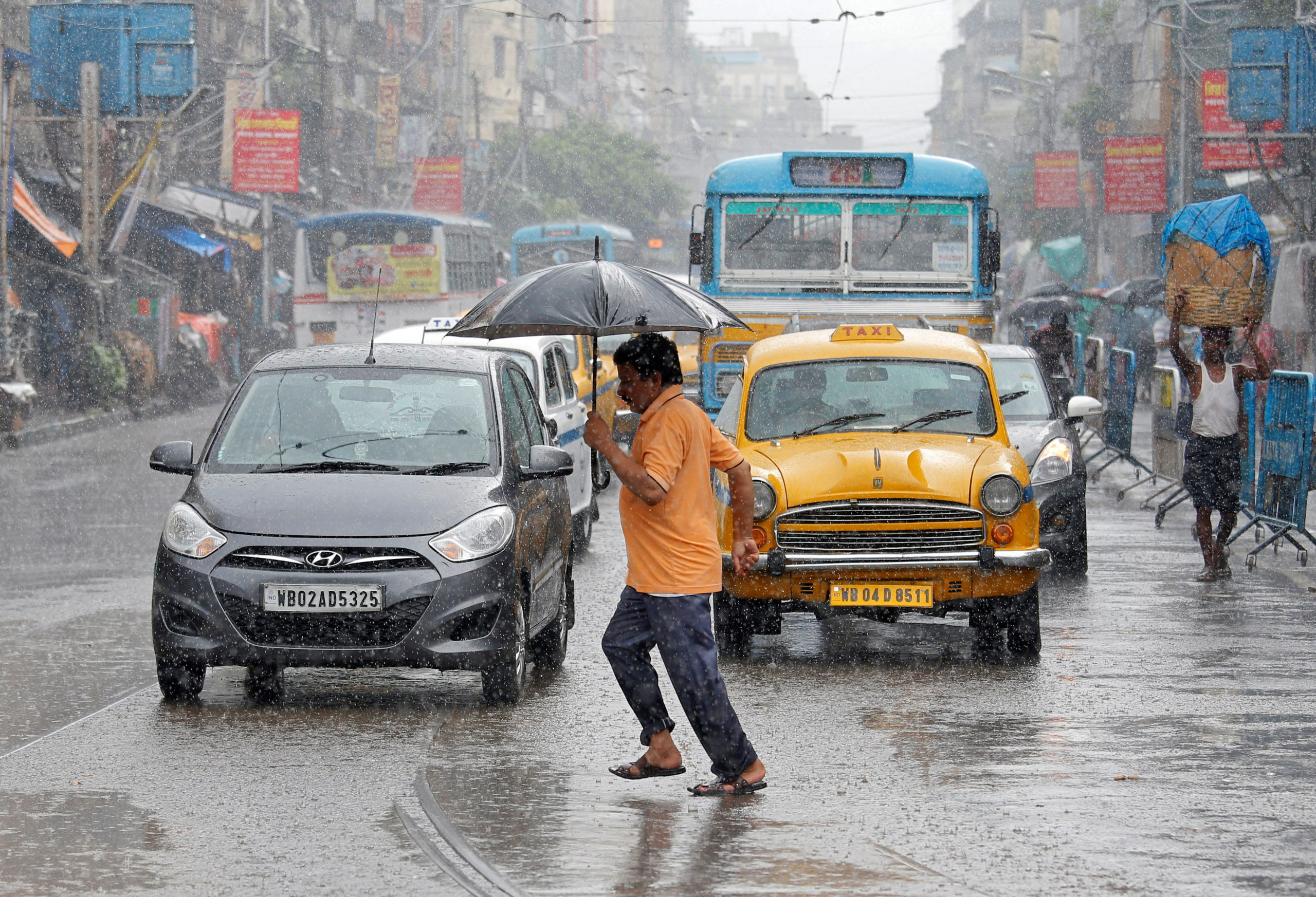 A man carrying an umbrella runs as he crosses a busy road during heavy rains in Kolkata