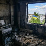Ukrainian national flag is seen through the window of an apartment destroyed during Russia's invasion of Ukraine in the town of Borodianka