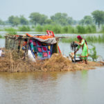A woman taking refuge is seen with her belongings, following rains and floods during the monsoon season in Sohbatpur
