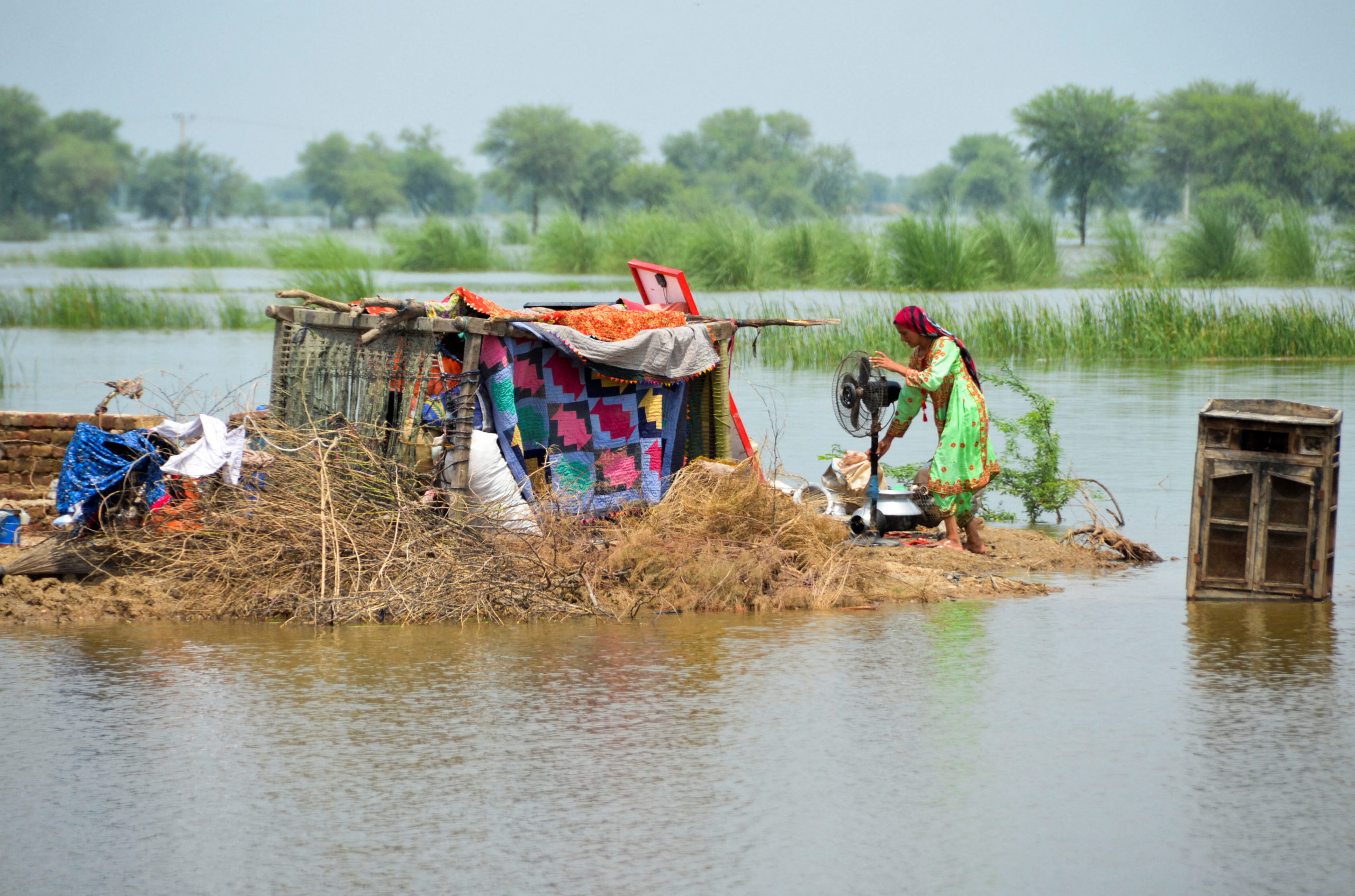 A woman taking refuge is seen with her belongings, following rains and floods during the monsoon season in Sohbatpur